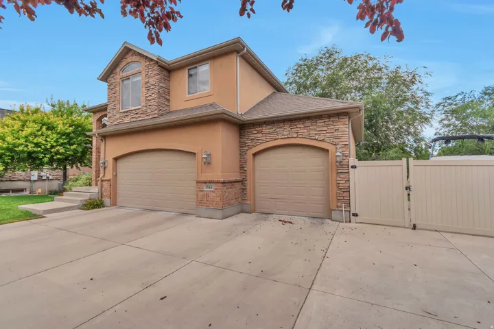 Stucco and stone facade home featuring a two-car garage, an additional single-car garage, and a concrete driveway