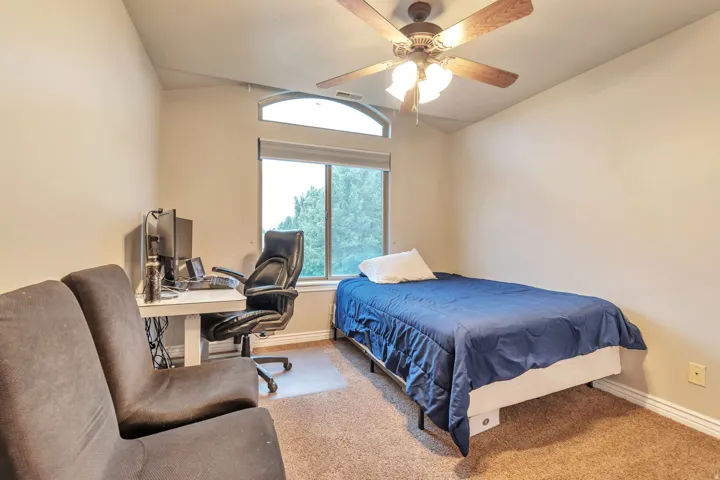 Carpeted interior space featuring a window with an arched transom, a ceiling fan with integrated lighting, and neutral wall tones