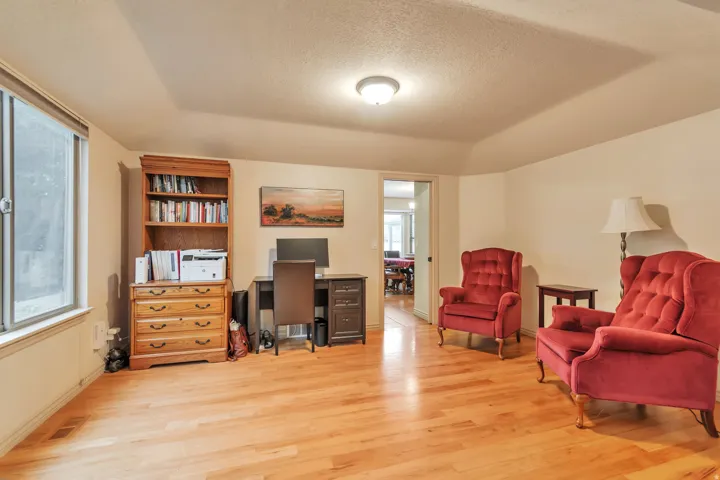 Warm-toned wood-finish flooring complements the neutral wall color in this versatile room