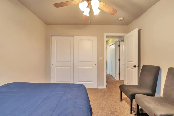 Bedroom featuring neutral wall paint, carpet flooring, a ceiling fan with light fixture, and white bi-fold closet doors