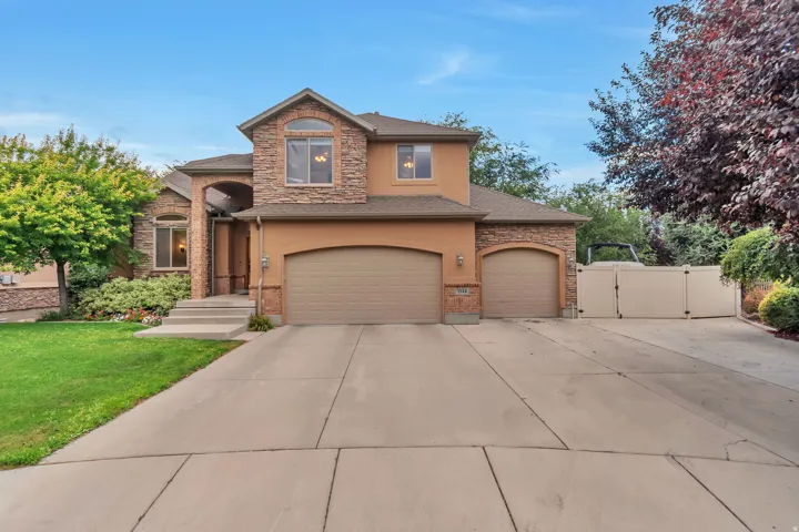 Stucco and stone facade home featuring an arched entry, two-car garage, and an additional single-car garage