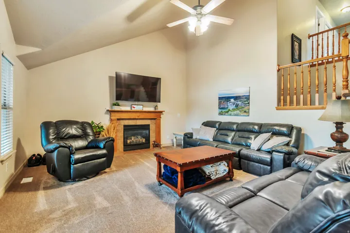 Living area featuring a vaulted ceiling and a ceiling fan with integrated lighting