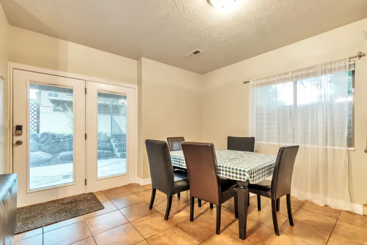Dining area featuring tile flooring, a large window with sheer white curtains, and double glass-paneled doors leading to the exterior