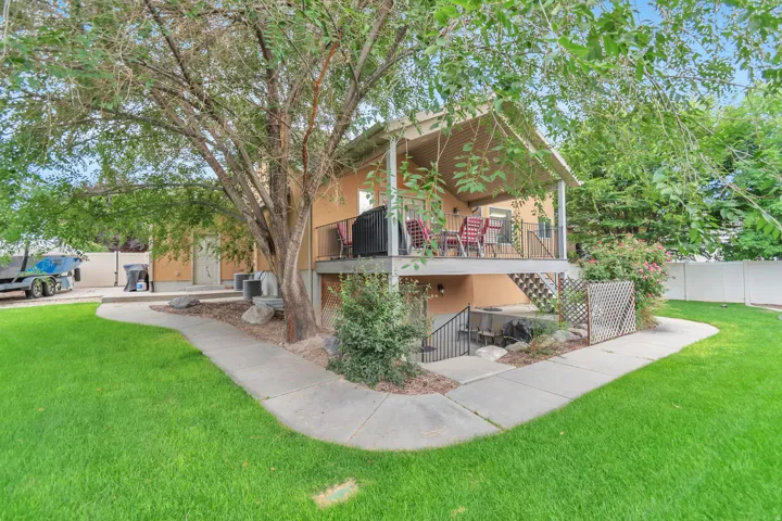 Two-story stucco property featuring an upper-level covered deck, a concrete patio below, and an exterior staircase with metal railings