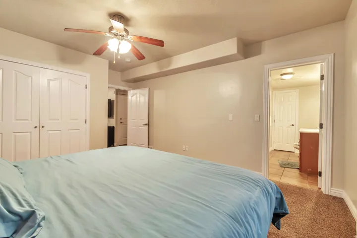 Warm-toned carpeting frames this space featuring a ceiling fan with wood-finish blades, recessed lighting, and white bi-fold closet doors