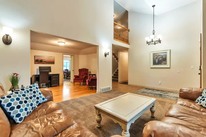 Spacious living area featuring vaulted ceilings, a two-story foyer, and an open concept to an additional room