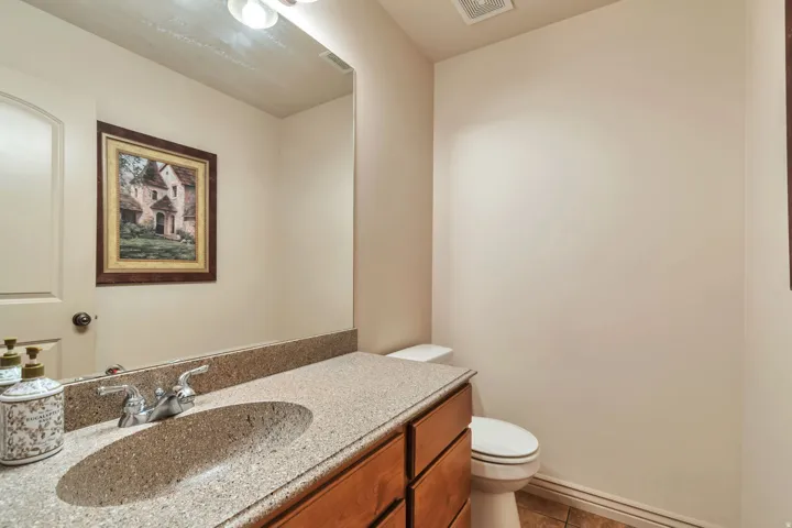 Bathroom vanity featuring a speckled countertop with an integrated sink, polished chrome faucet, and wood-finish cabinetry