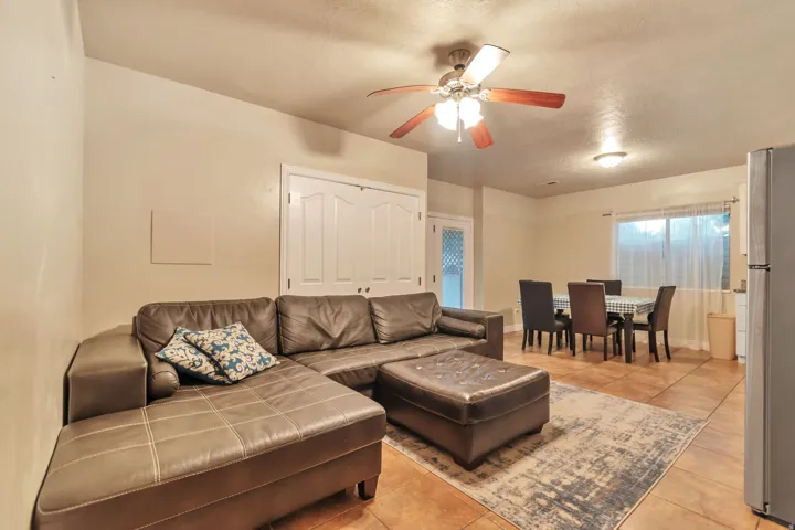 Open-concept living area featuring warm-toned tile flooring, light-colored walls, and a ceiling fan with integrated lighting