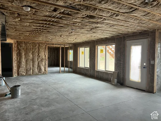 Open concept space featuring multiple windows, an exterior door, and exposed framing