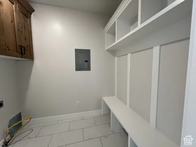Built-in white storage cabinetry with cubbies, integrated bench seating, wall-mounted wood-finish upper cabinetry, and large-format tile flooring