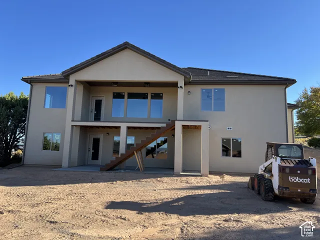 Two-story stucco exterior with multiple windows and a covered upper-level patio