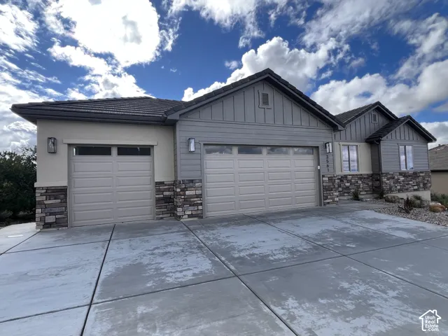 Exterior featuring a combination of horizontal lap and vertical board-and-batten siding, stone veneer accents, concrete driveway, and a three-car garage
