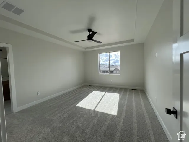 Bright secondary bedroom featuring neutral wall finishes, ceiling fan, and striped wood-finish flooring with natural light from large window overlooking the surrounding landscape