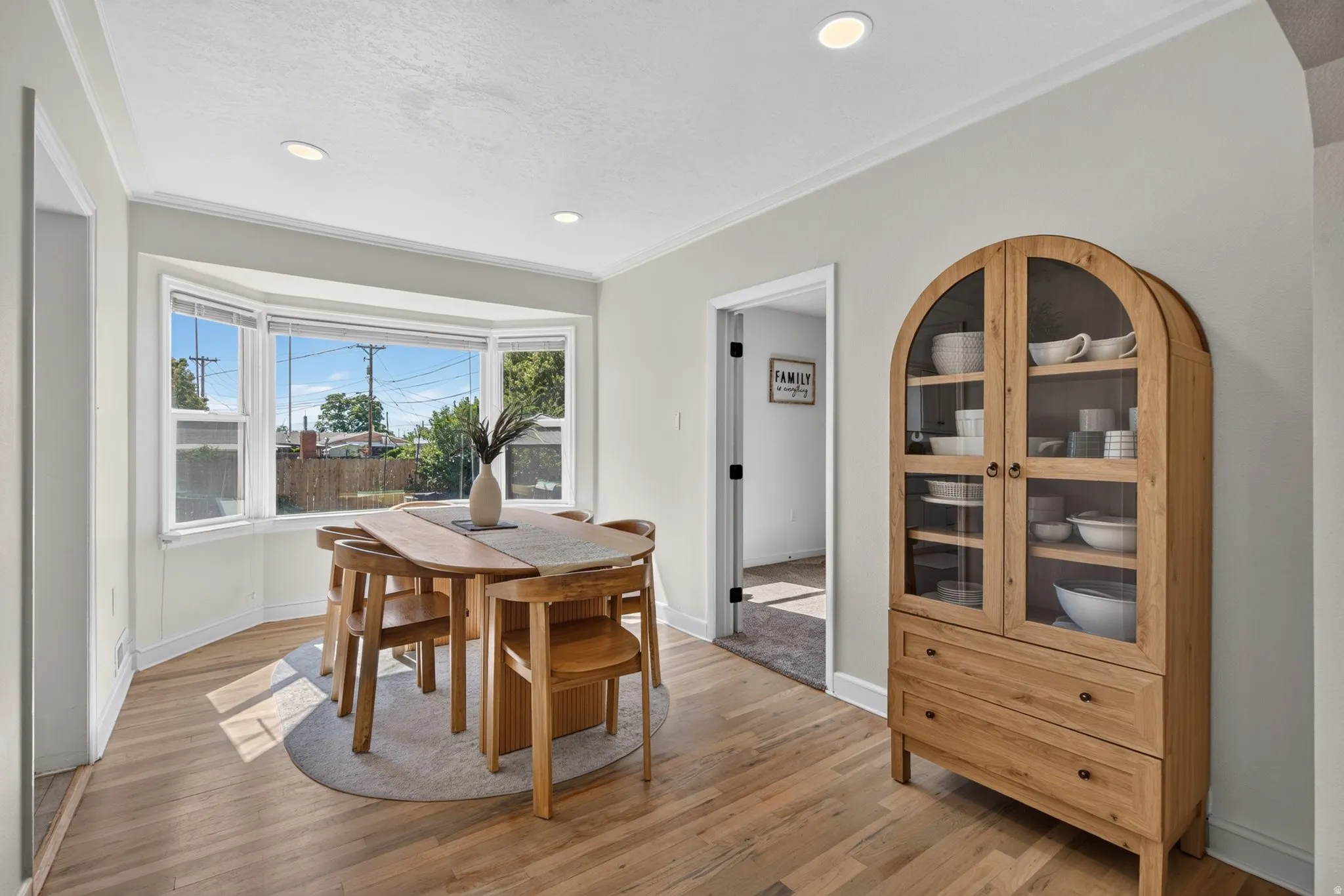 Dining area featuring a bay window, recessed lighting, crown molding, and wood-finish flooring