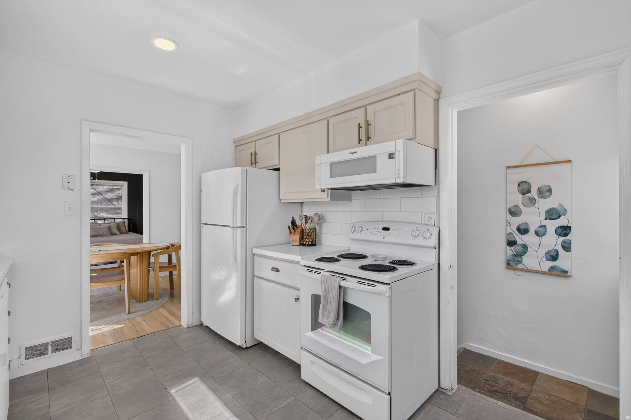 Kitchen featuring white appliances, a subway tile backsplash, and light-toned upper cabinetry