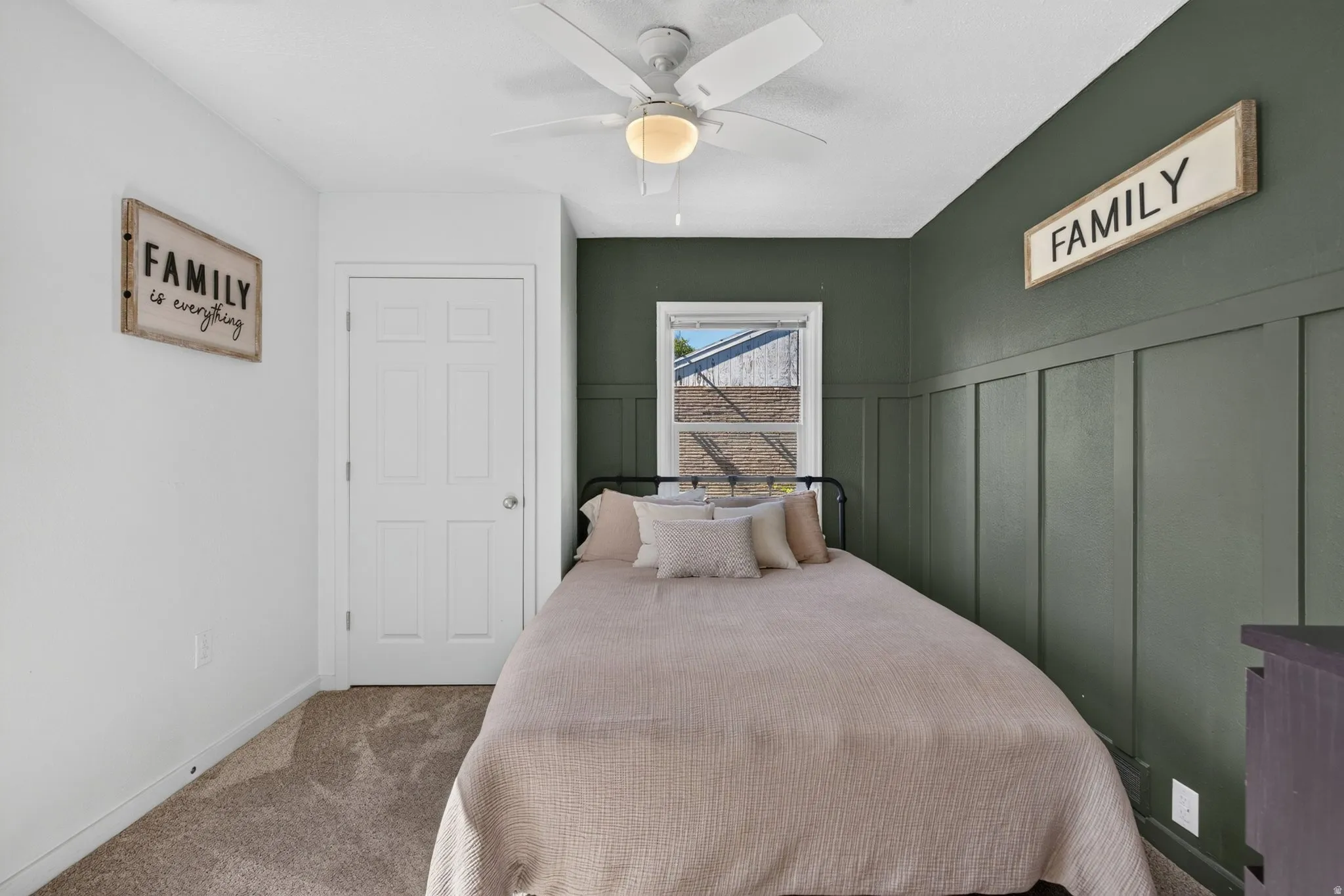 Carpeted room featuring a ceiling fan with integrated lighting, a four-panel interior door, and a window with white trim