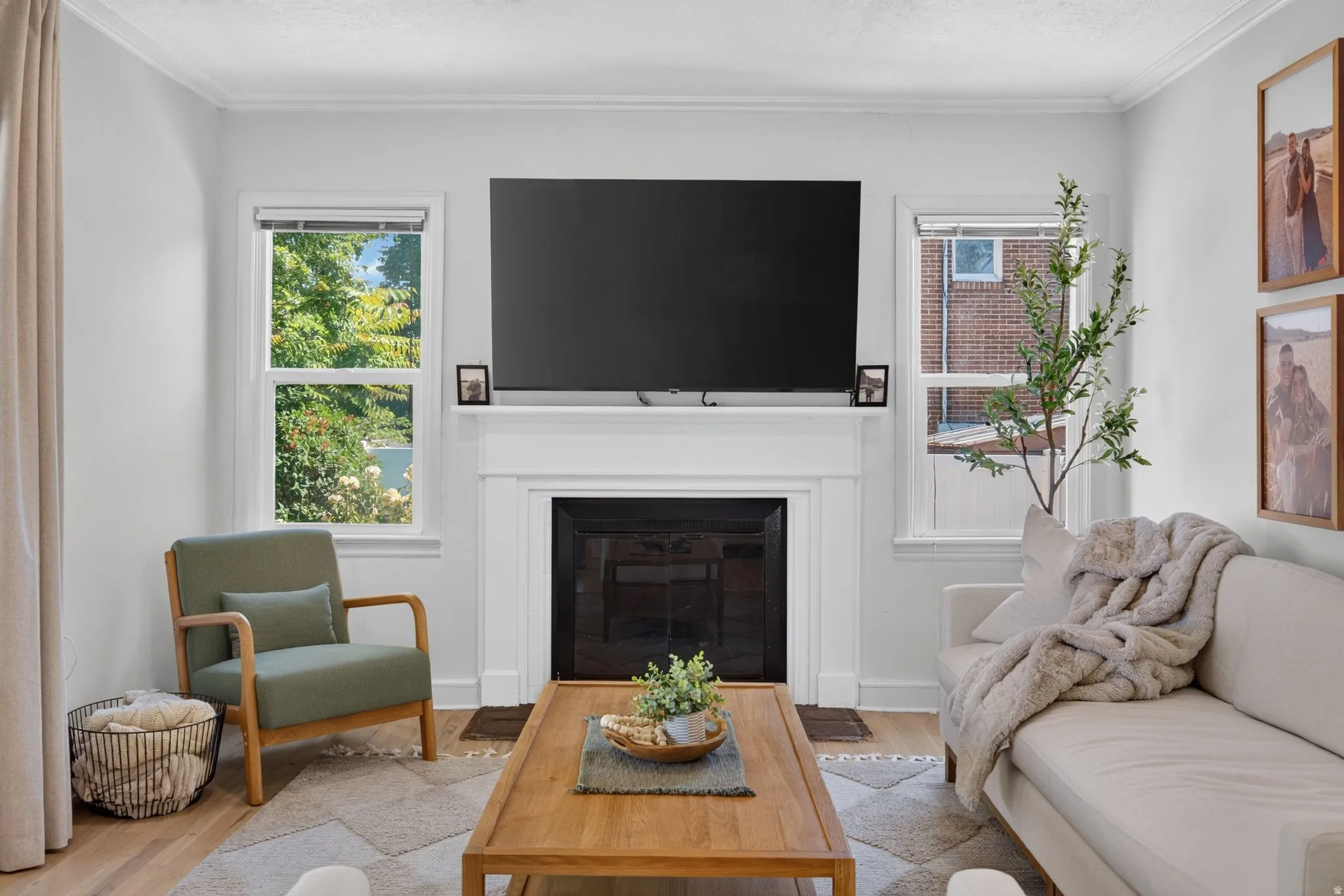 Living area featuring a fireplace with a white mantel, crown molding, and light wood-finish flooring