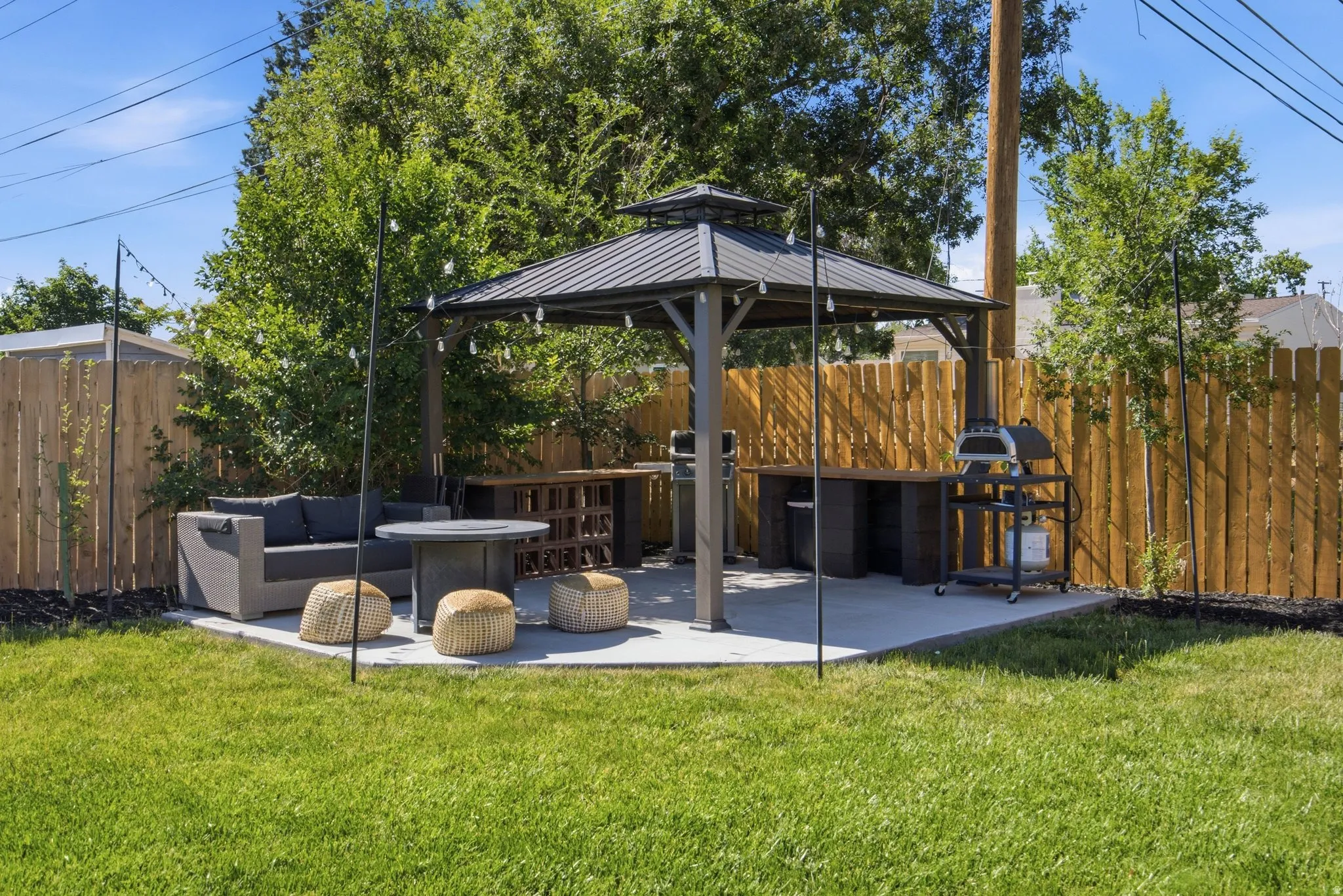 Fenced backyard featuring a concrete patio with a built-in gazebo