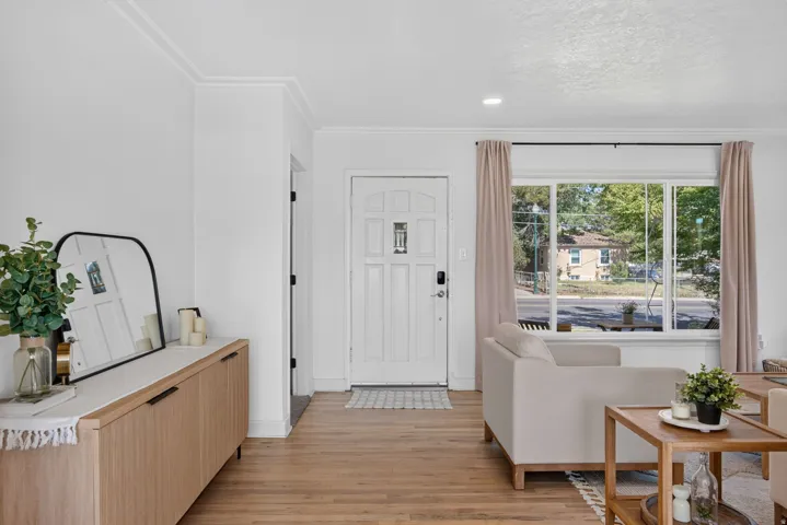 Entryway featuring a panel door, wood-finish flooring, and crown molding