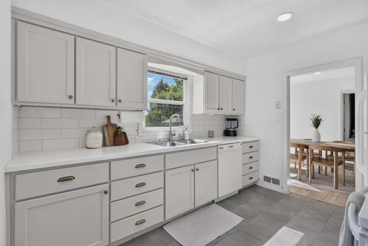 Kitchen featuring light gray cabinetry with cup pulls and knobs, white subway tile backsplash, and light-toned countertops