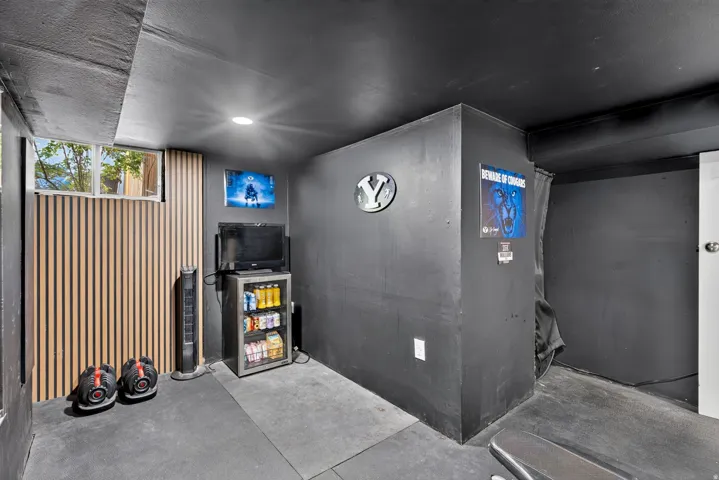 Recessed lighting illuminates a space featuring dark-toned walls and ceiling, a window, and wood-finish paneling