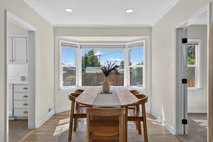 Bay window with natural light, recessed lighting, crown molding, wood-finish flooring, and light-colored walls