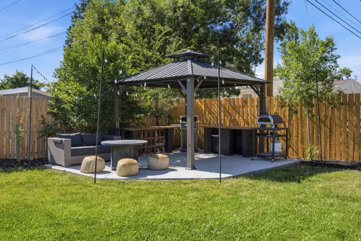 Fenced backyard featuring a concrete patio with a built-in gazebo