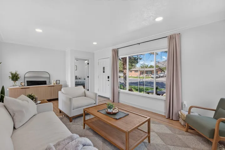 Bright living area featuring wood-finish flooring, recessed lighting, and crown molding