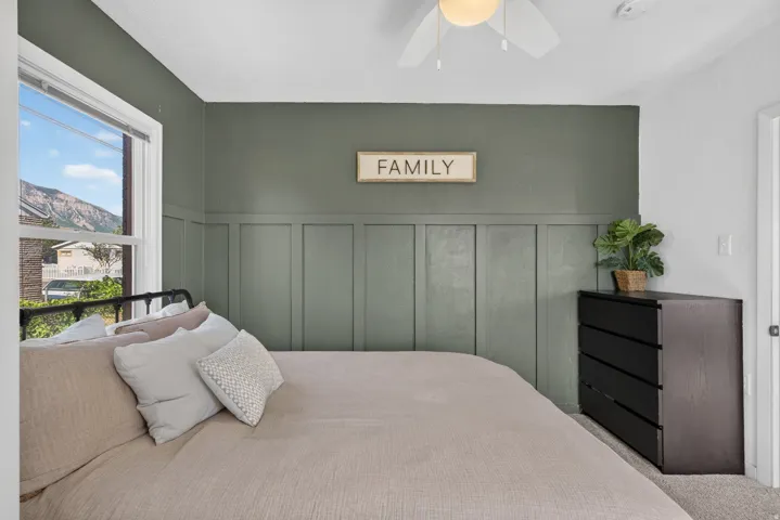 Bedroom featuring an accent wall with wainscoting detail and a white-framed window