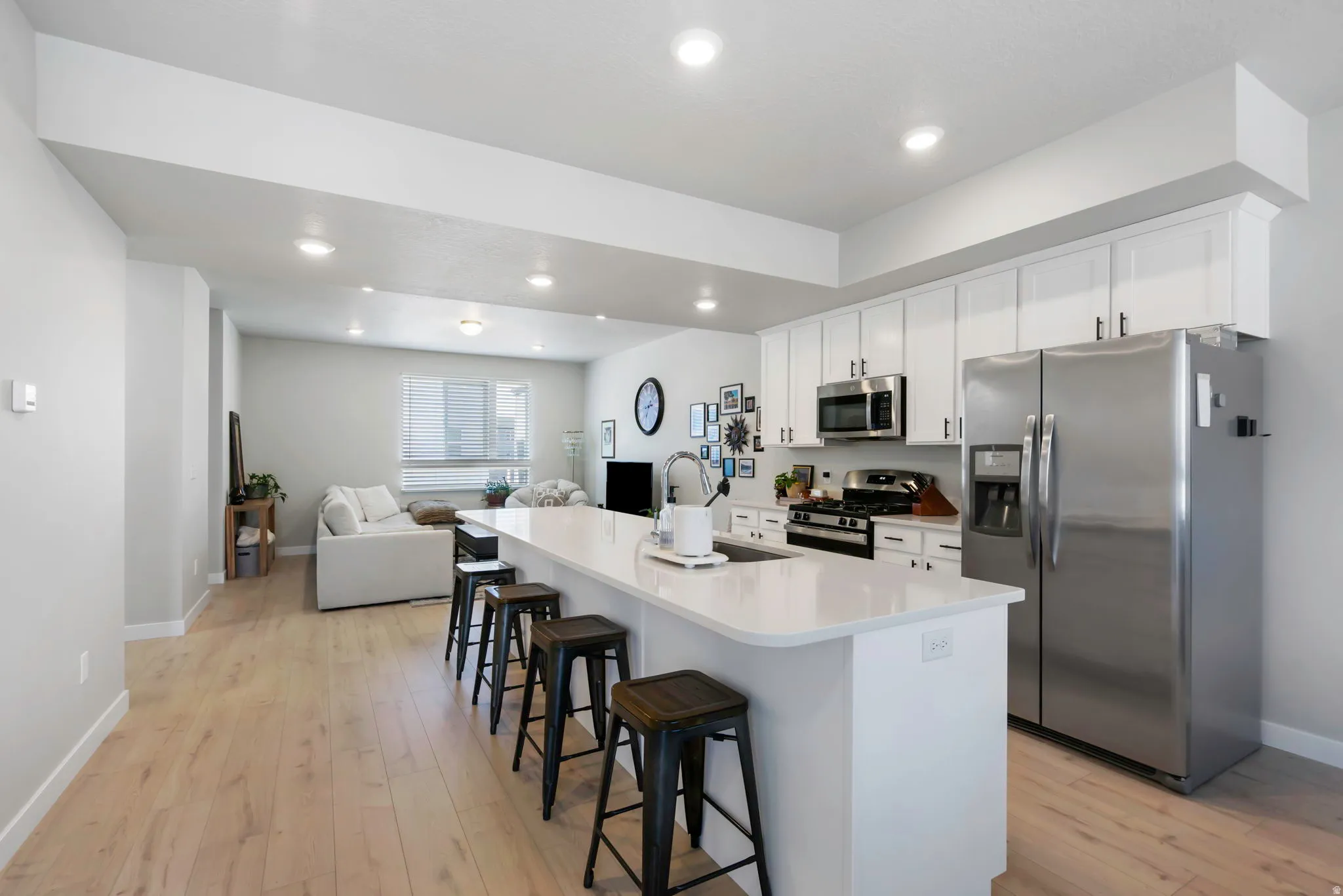 Open-concept living space with light wood-finish flooring, white walls, and recessed lighting