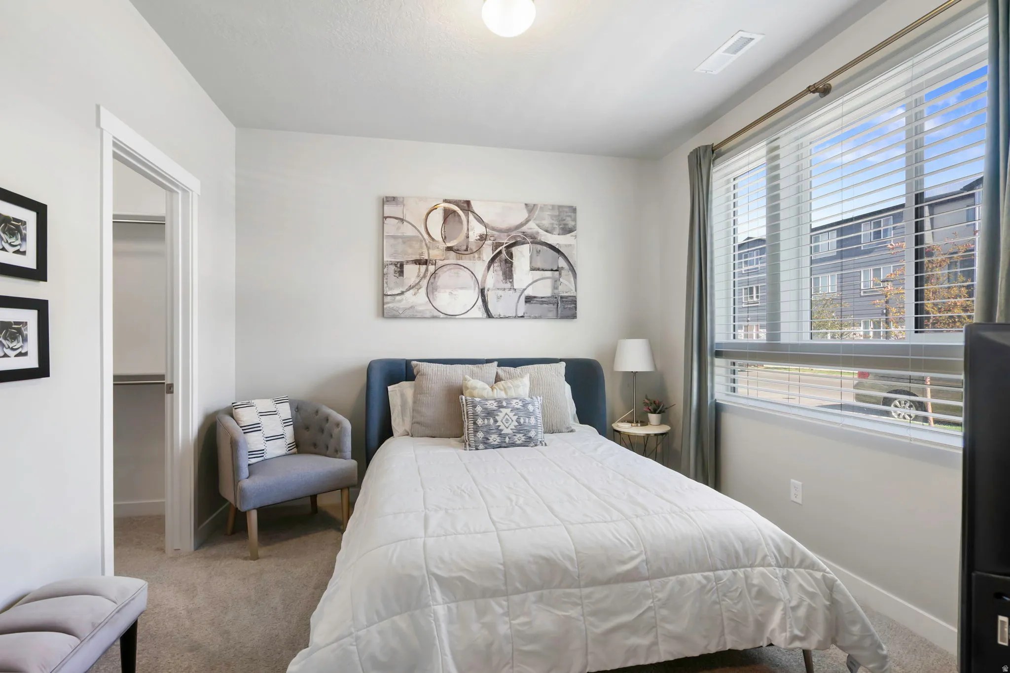 Bedroom featuring light neutral wall paint, carpet flooring, a built-in closet with shelving, and large windows with blinds