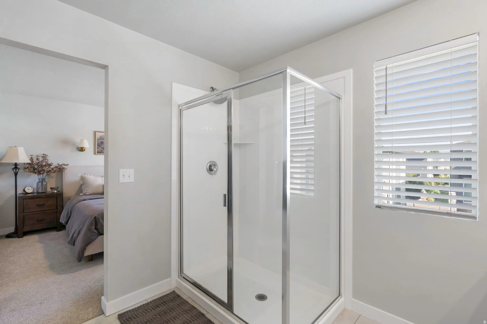 Enclosed glass shower stall with a chrome frame, white shower pan, and built-in shelving