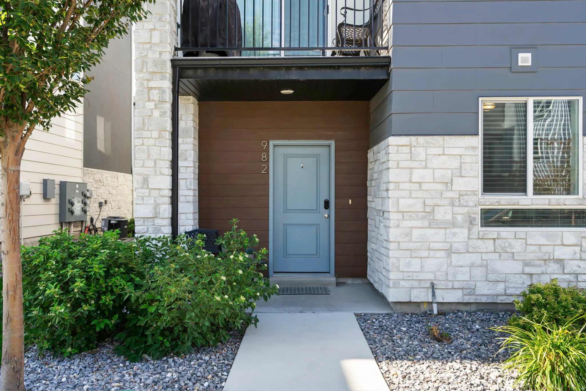 Modern multi-texture facade featuring light gray stone, horizontal brown siding, and dark gray horizontal paneling