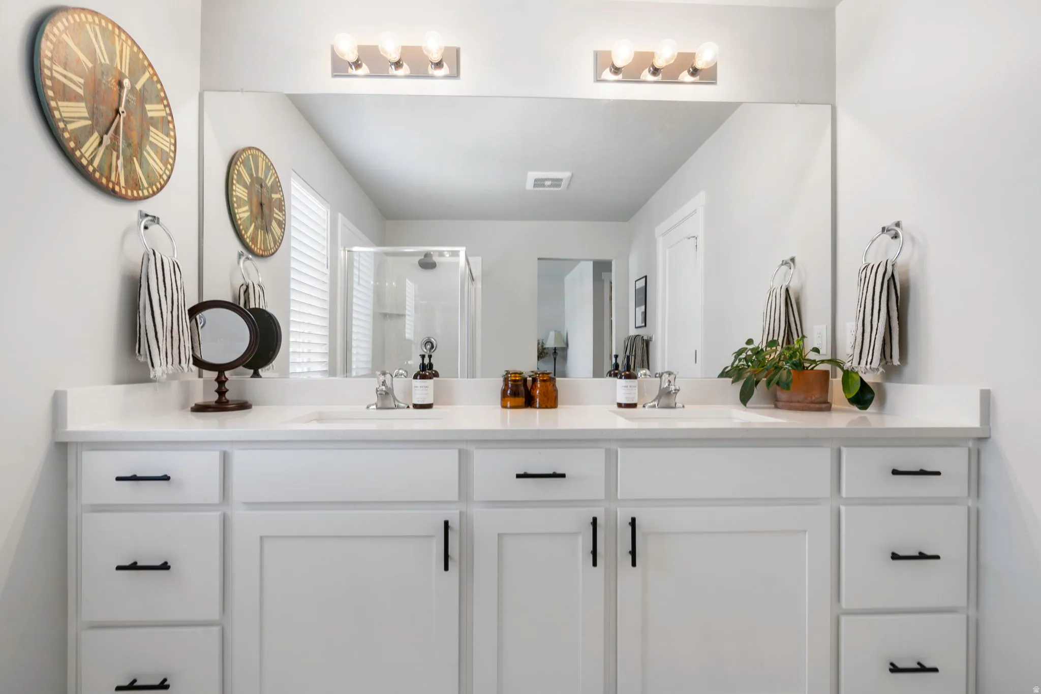 Dual vanity with white cabinetry, matte black hardware, and an expansive countertop