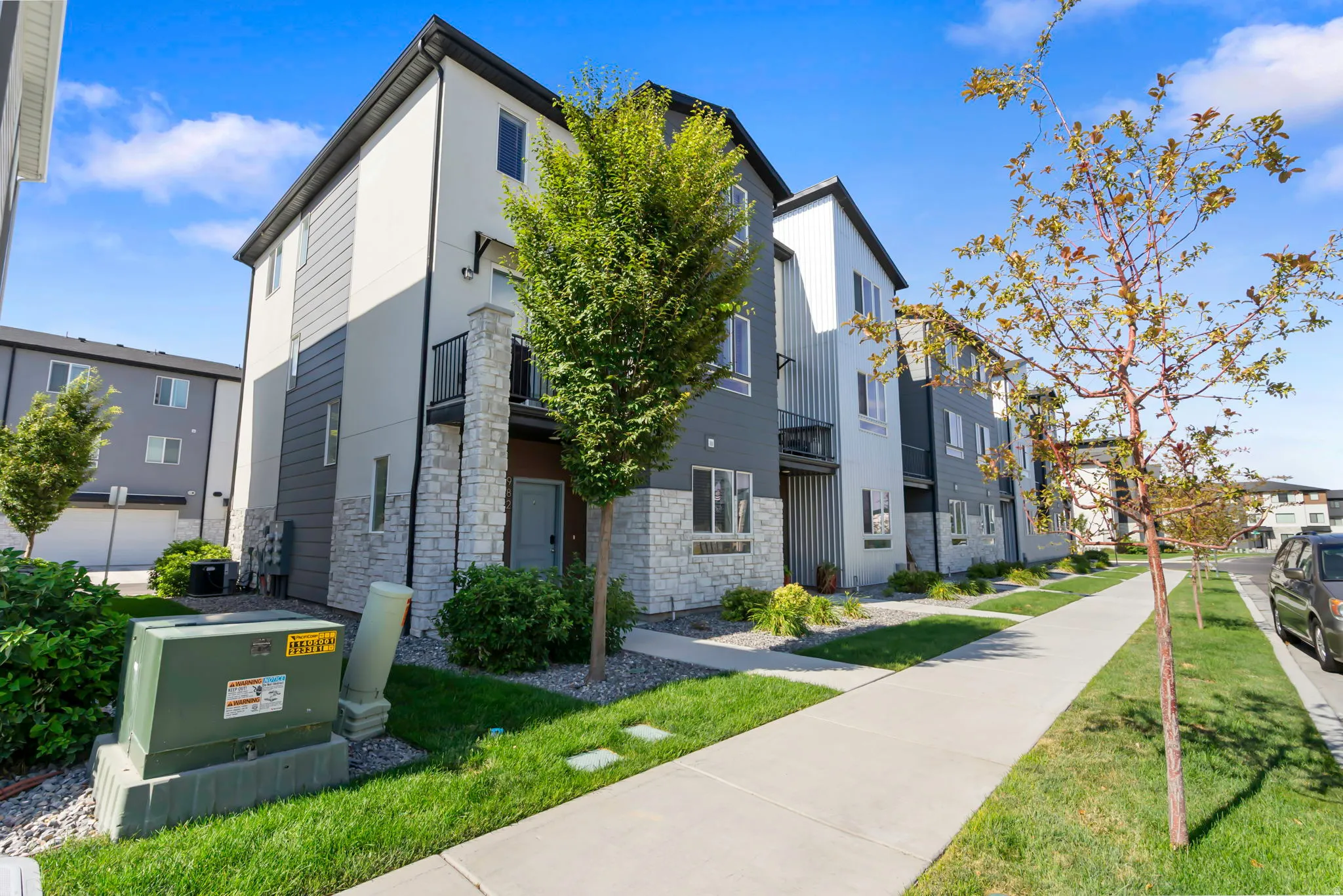 Contemporary townhouse exterior featuring a multi-tone facade with white stucco and dark gray siding