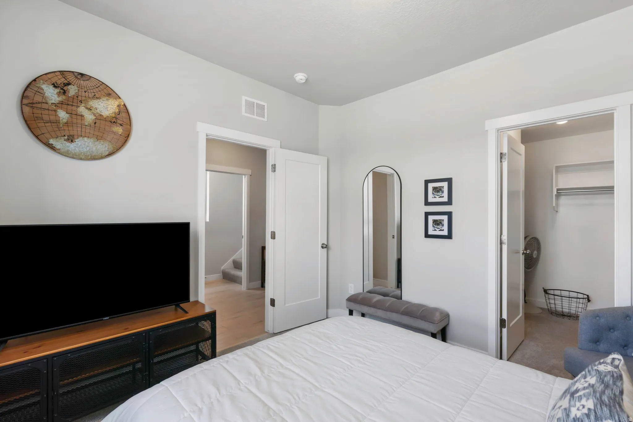 Light-toned walls with contrasting white trim, featuring an open doorway to a closet with built-in shelving and hanging rod