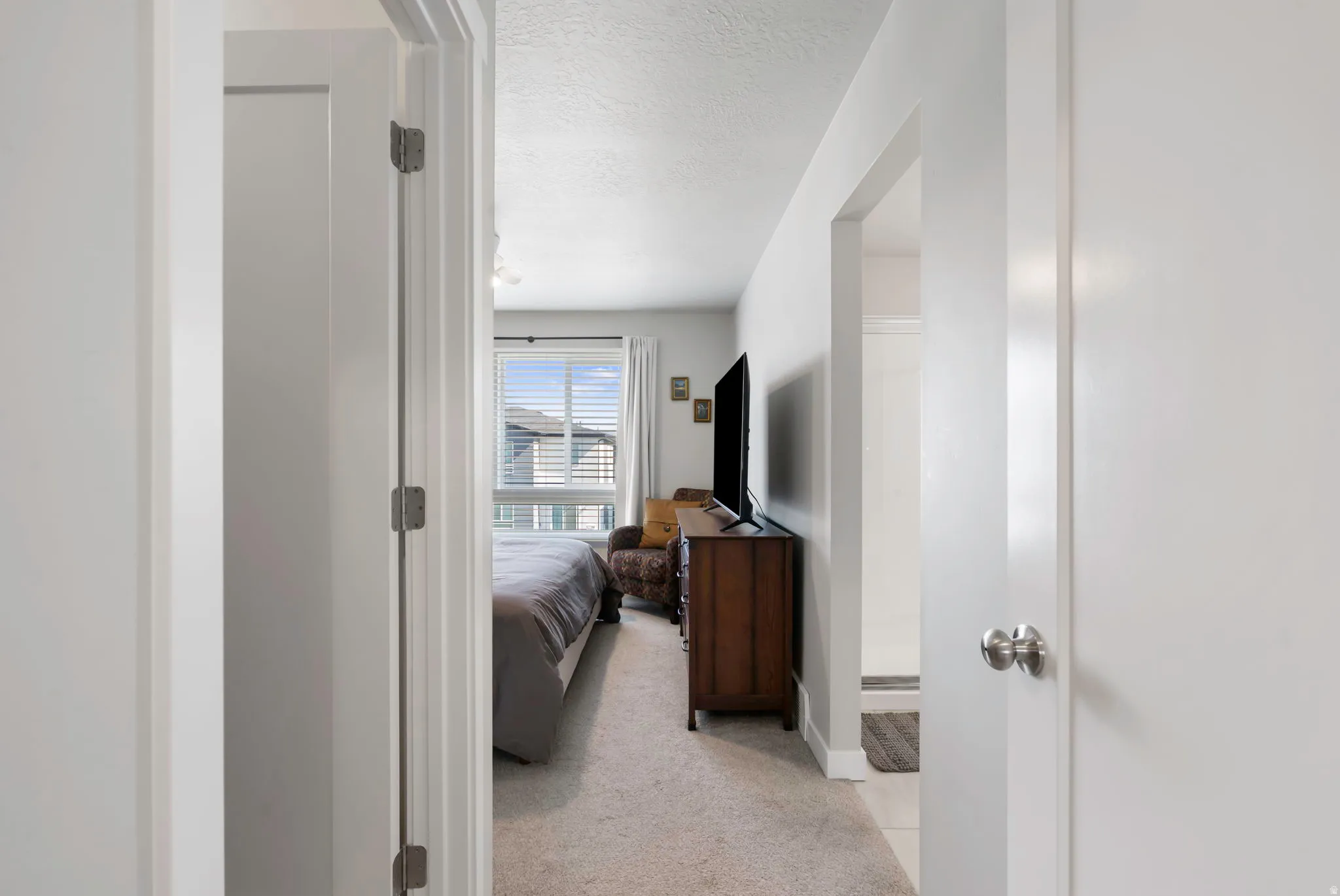 Carpeted room with a large window featuring horizontal blinds