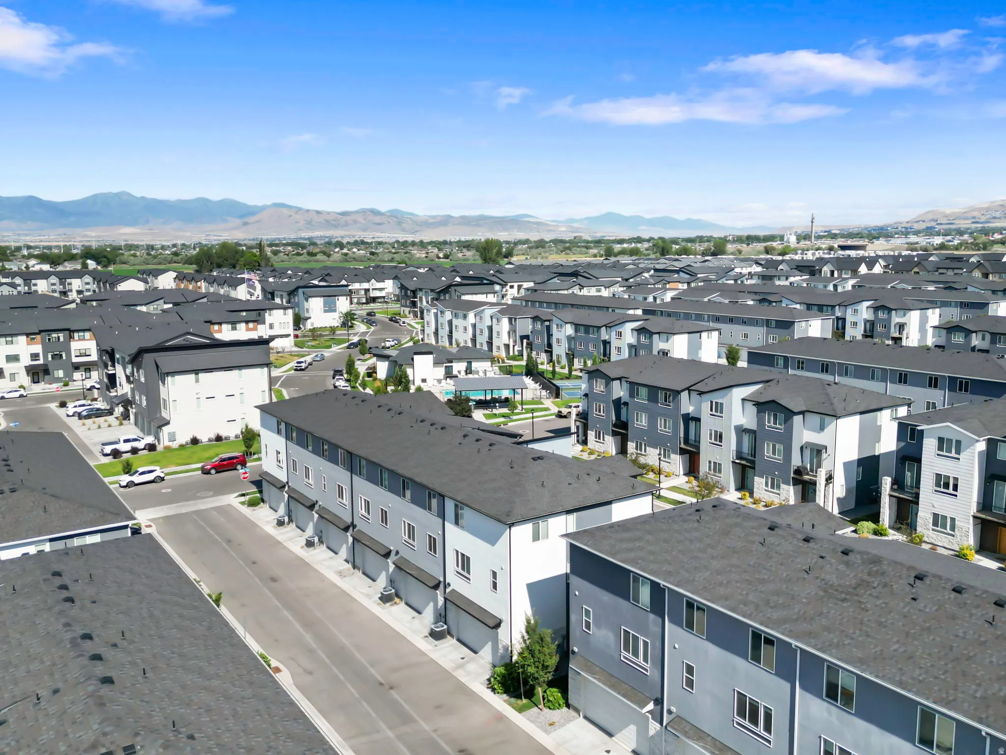 Modern residential community featuring multi-story townhomes with dark roofs and light-toned siding