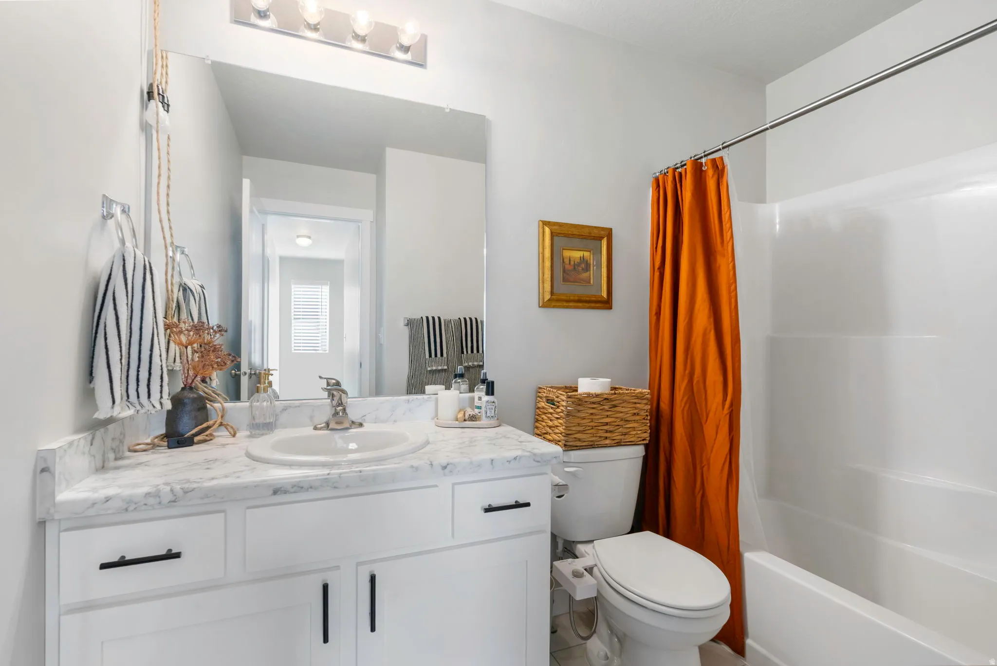 Bathroom featuring a white vanity with a marble-look countertop, an integrated sink, and black hardware