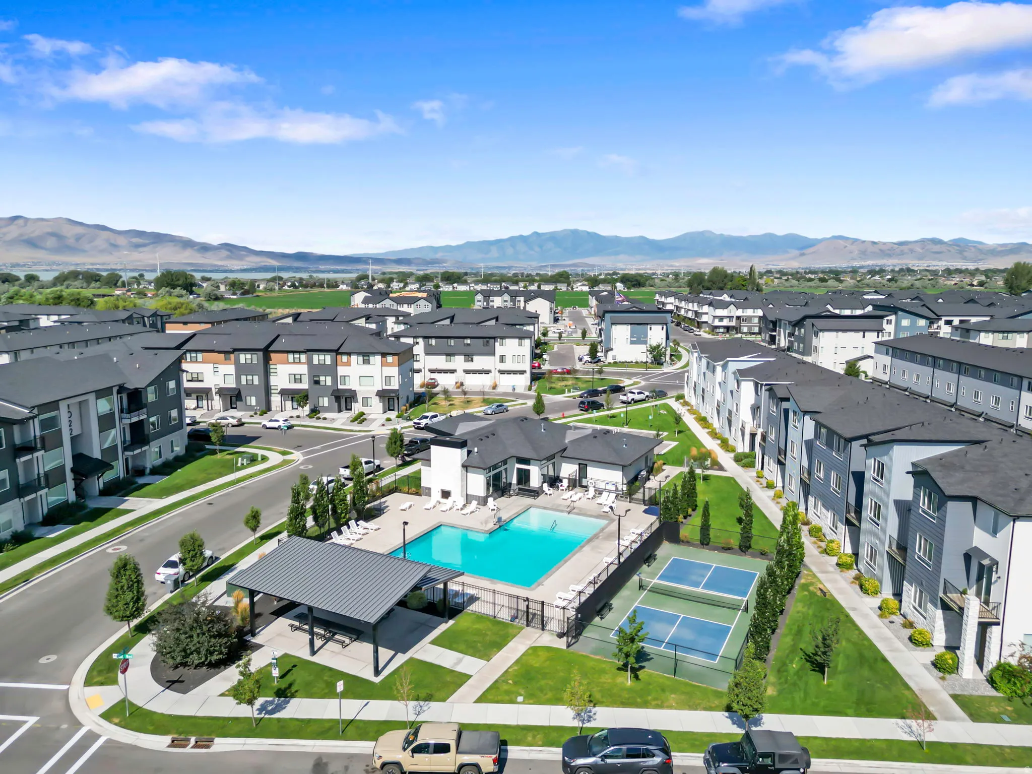 Aerial perspective showcasing a community with multi-story buildings, a central swimming pool, and a tennis court