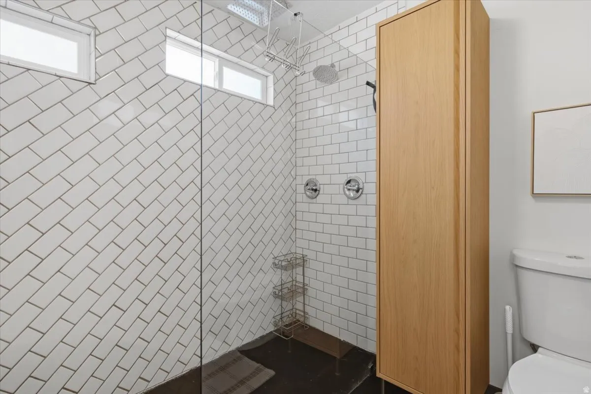 Shower enclosure featuring subway tile walls, dual shower controls, and a rainfall showerhead