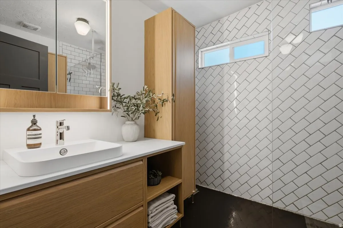 Modern bathroom vanity featuring a rectangular vessel sink, wood-finish cabinetry, and an illuminated mirrored medicine cabinet