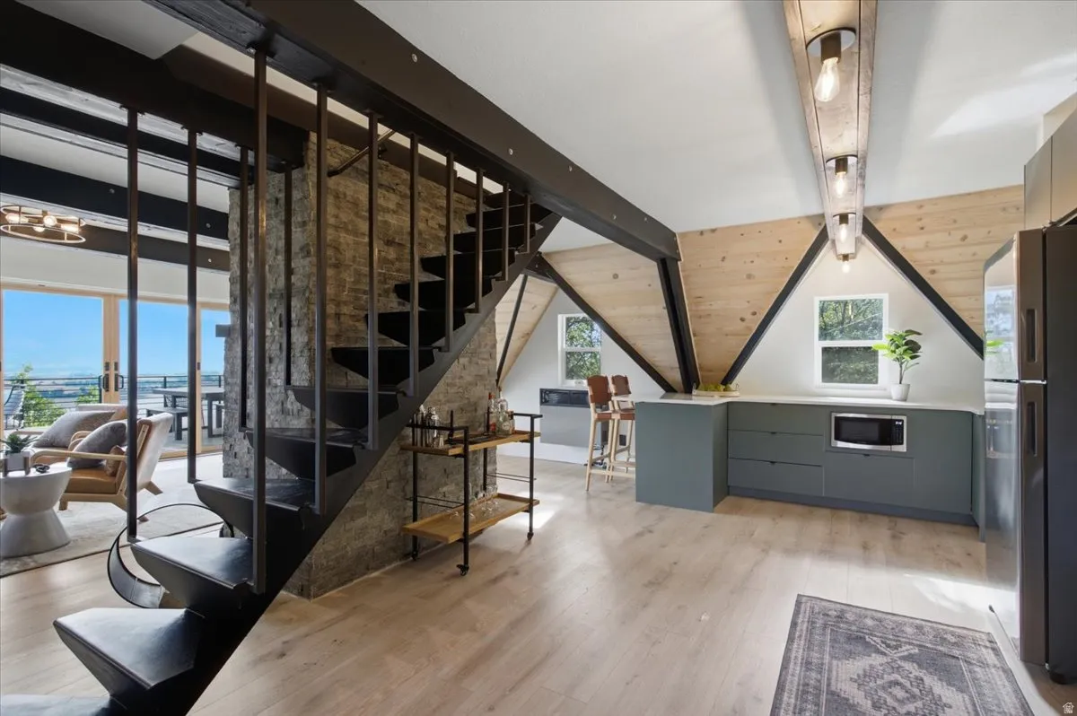 Open-concept living space featuring a sculptural black metal staircase, a natural stone accent wall, and wood-finish flooring