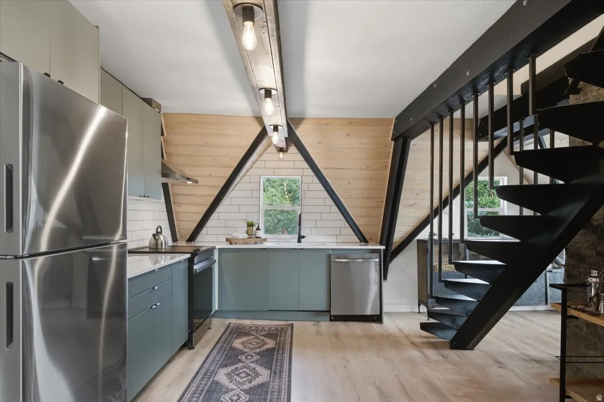 Kitchen featuring stainless steel appliances, light wood-finish flooring, light gray cabinetry, white subway tile backsplash, and a window with exterior foliage