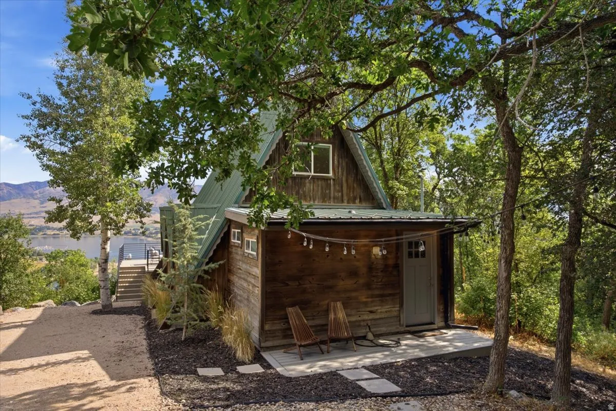 A-frame structure with natural wood siding, featuring a green metal roof and a prominent upper-level window