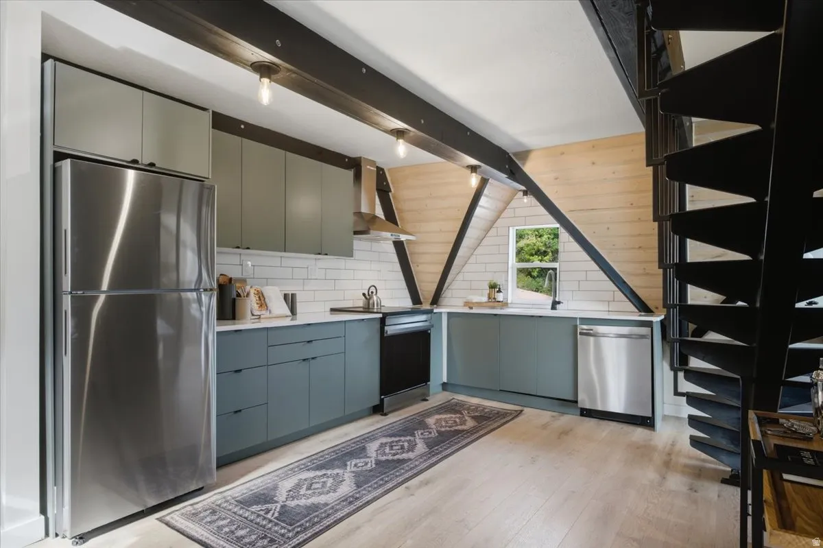 Modern kitchen featuring stainless steel appliances, light wood-finish flooring, and subway tile backsplash