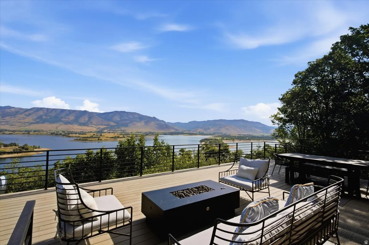 Deck with cable railing overlooking a large body of water, distant mountains, and natural landscaping