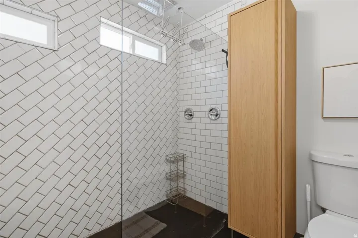 Shower enclosure featuring subway tile walls, dual shower controls, and a rainfall showerhead