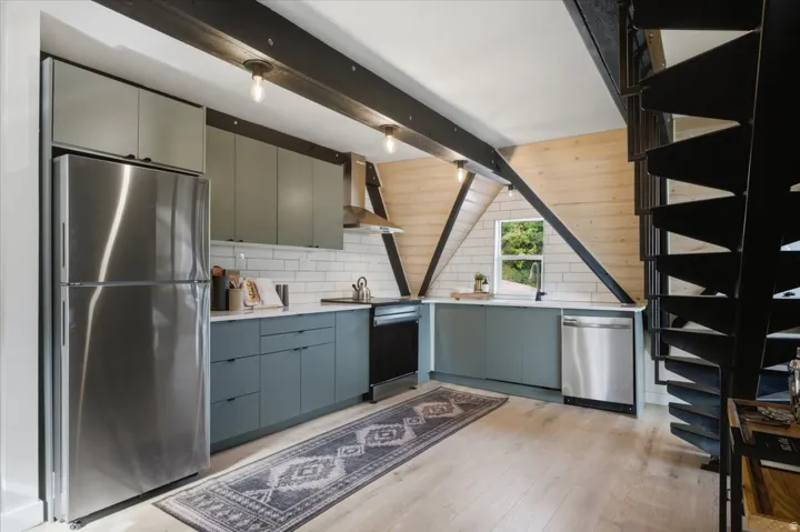 Modern kitchen featuring stainless steel appliances, light wood-finish flooring, and subway tile backsplash