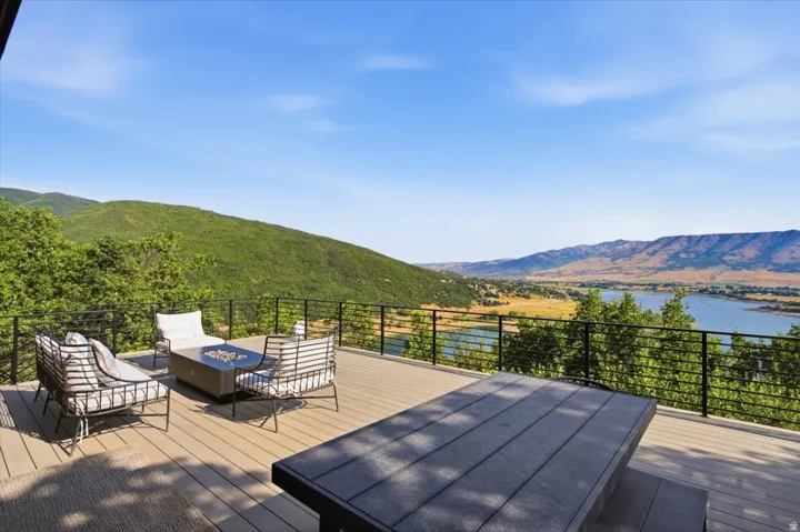 Expansive outdoor deck featuring composite decking, a linear railing system, and a mountain and lake backdrop